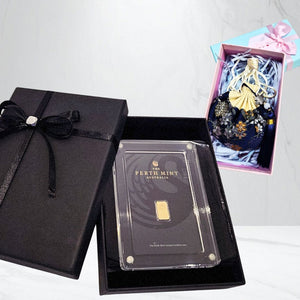 Gold bar in a clear case with 'The Perth Mint Australia' branding, inside an open black gift box.